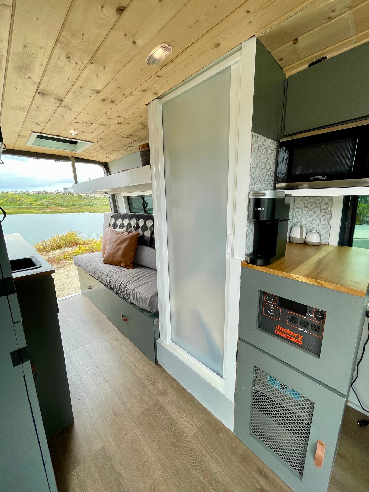Inside a bright RV rental: wooden ceiling, kitchen with appliances, comfortable seating, and a peaceful lake view. — photo 12