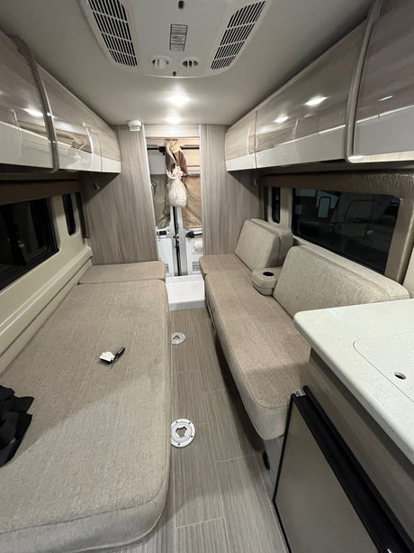 Inside a cozy **rv rental**: two sleeping/seating benches, overhead cabinets, and a compact kitchen. Ready for adventures.