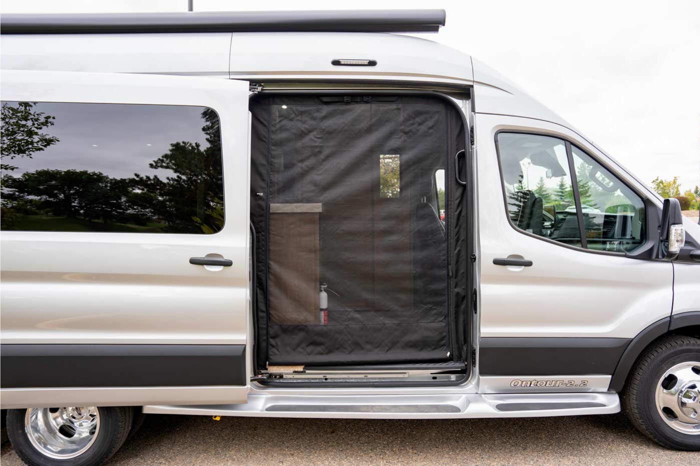 This silver RV rental camper van features an open sliding side door with a black mesh screen, offering a glimpse inside. — photo 13