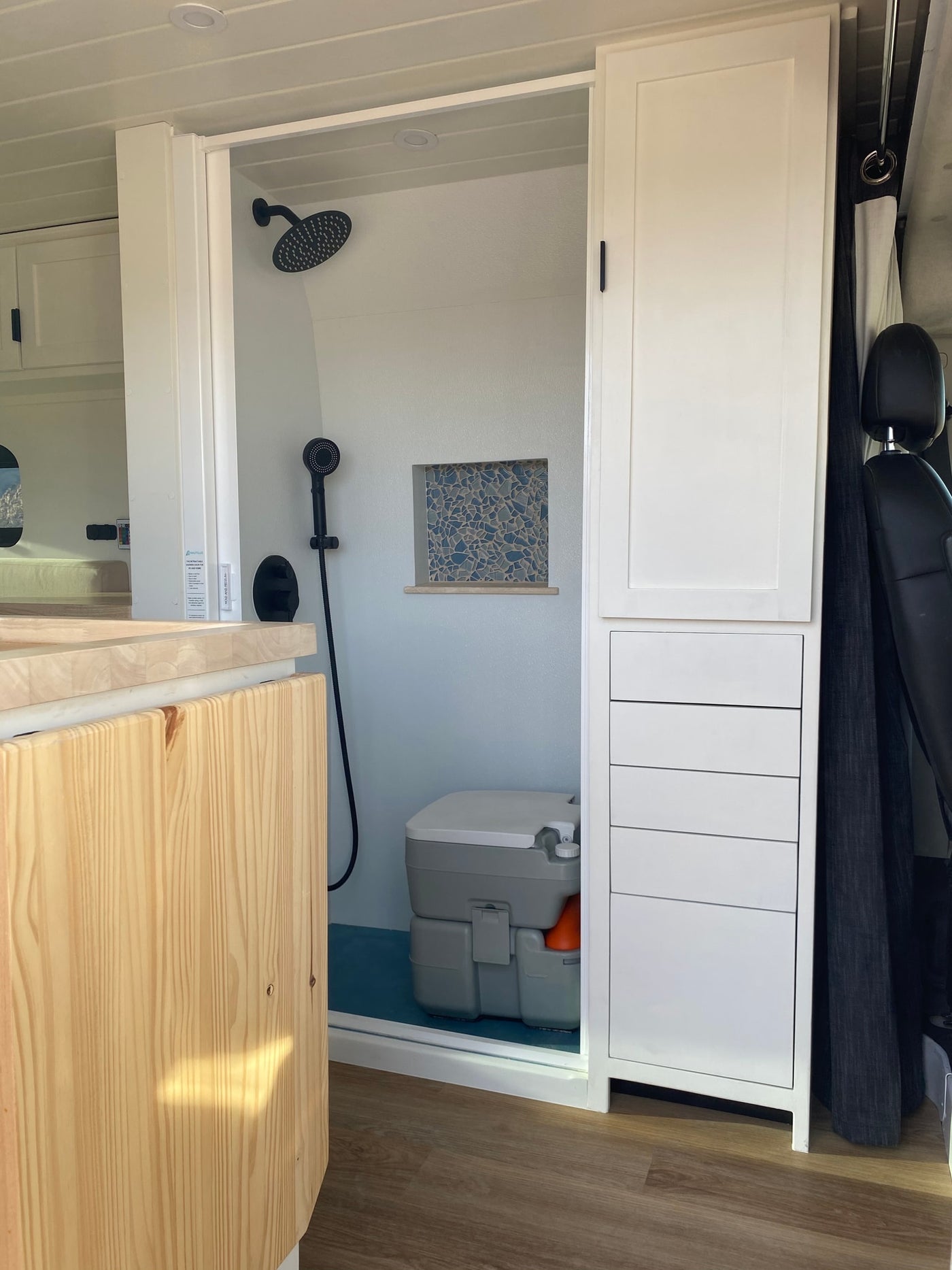 RV rental's compact bathroom includes a shower, portable toilet, and integrated storage. Designed for comfortable mobile living. — photo 3