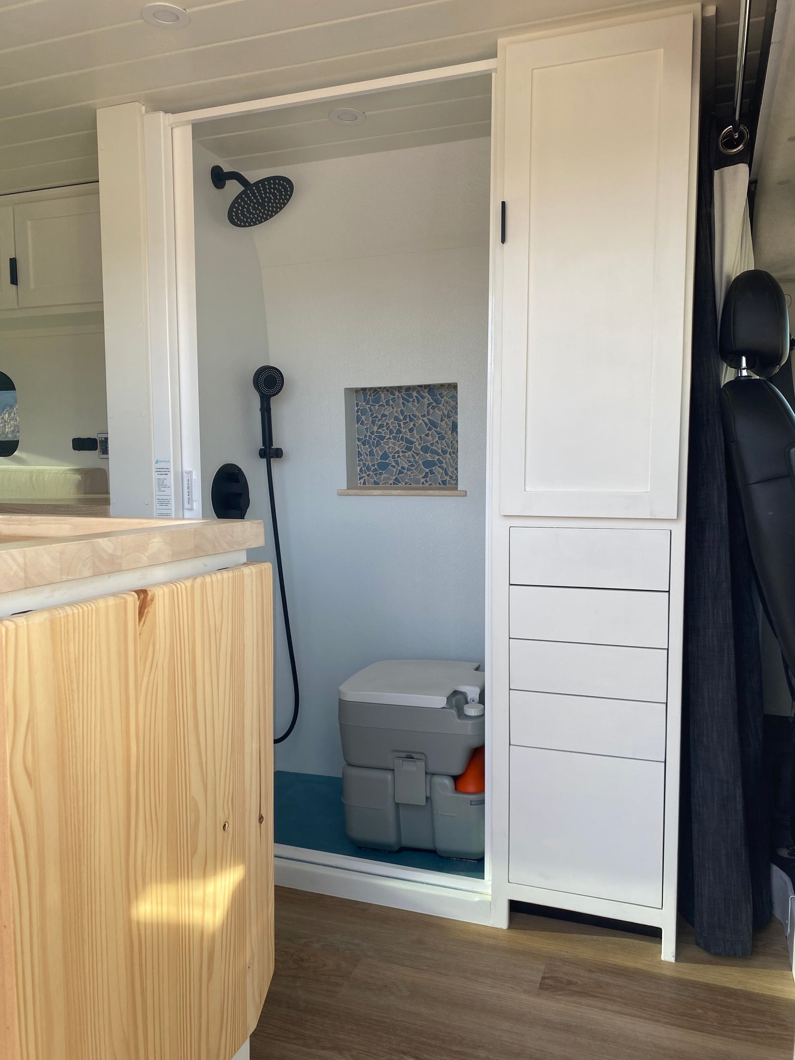 RV rental's compact bathroom includes a shower, portable toilet, and integrated storage. Designed for comfortable mobile living.