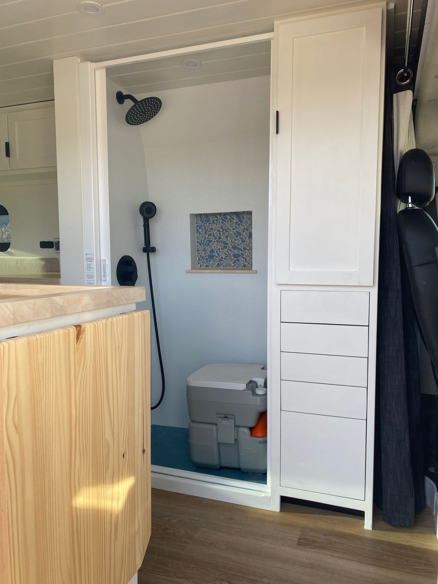 RV rental's compact bathroom includes a shower, portable toilet, and integrated storage. Designed for comfortable mobile living.