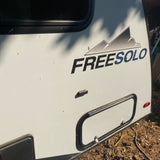 Exterior of a Freesolo RV rental, showing its side, prominent logo, upper window, lower storage hatch, and rear taillight.