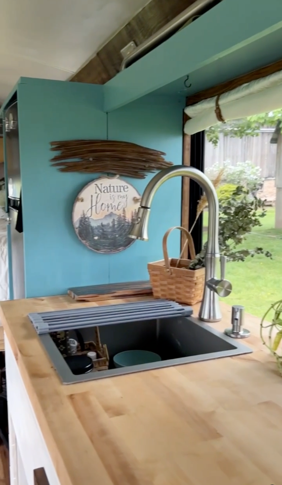 Explore this RV rental's nature-inspired kitchen: teal wall, wood counters, and functional sink area. Your cozy home on the road! — photo 9