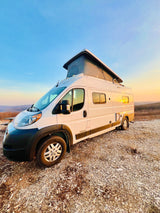 White pop-top RV rental parked at a scenic sunset overlook. Ideal for van life and outdoor adventures.
