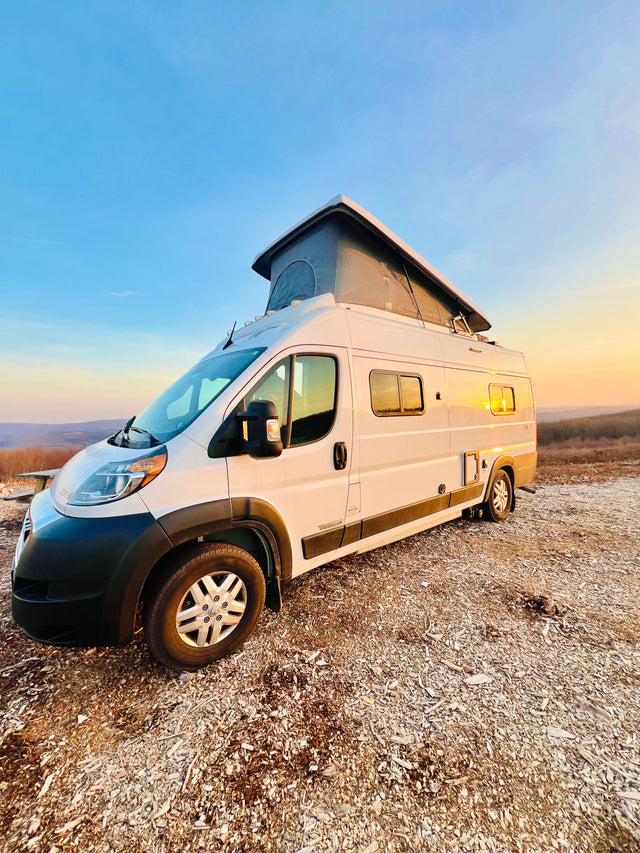 White pop-top RV rental parked at a scenic sunset overlook. Ideal for van life and outdoor adventures.