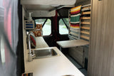 This RV rental features a functional camper van interior with a kitchen sink, convertible bed, and a versatile table setup.