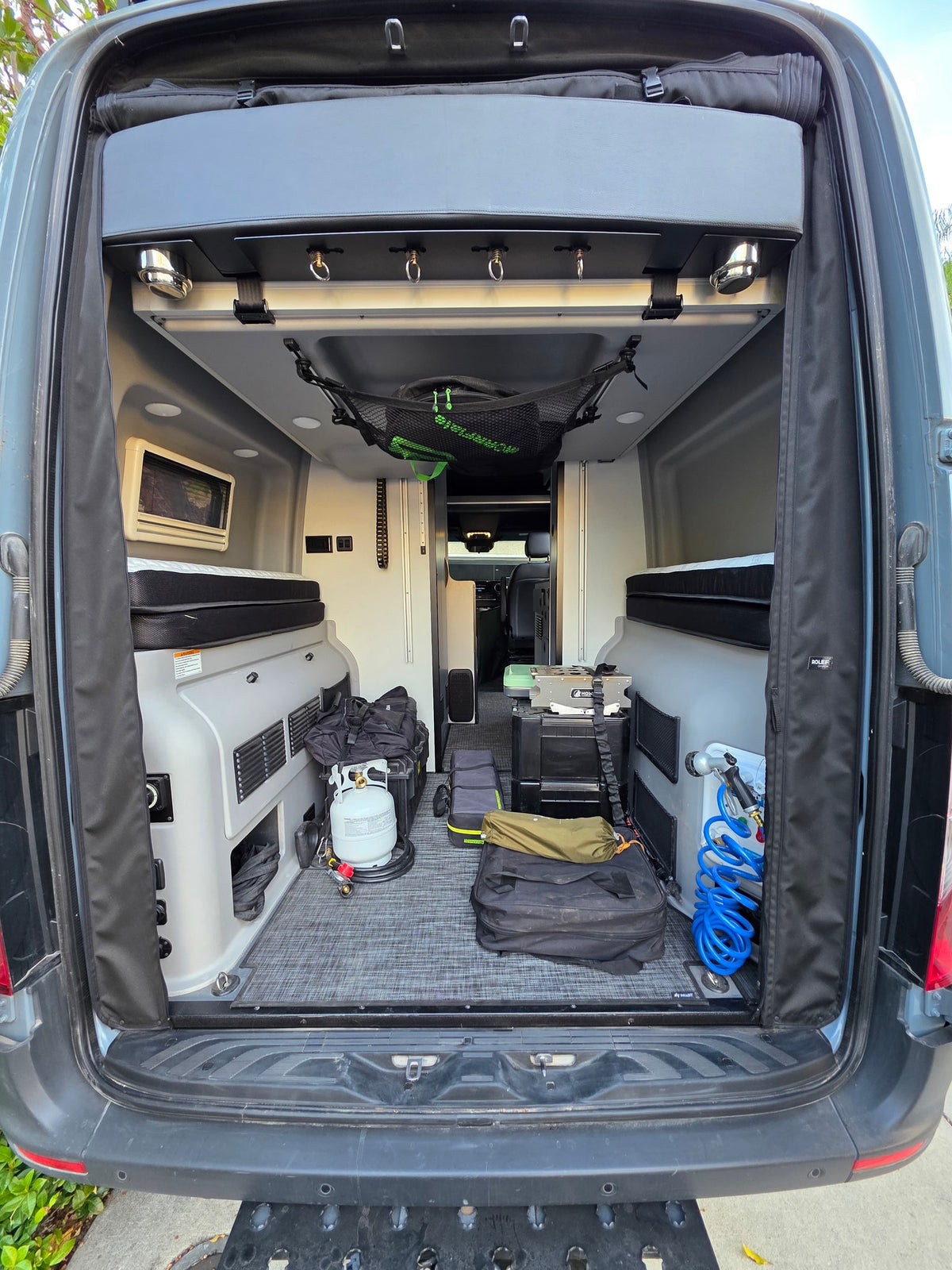 Packed RV rental camper van interior, featuring beds, camping stove, propane, and organized gear for trips. — photo 6