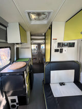 This bright **rv rental** showcases its well-equipped kitchen area, comfortable bench seating, and essential power controls.