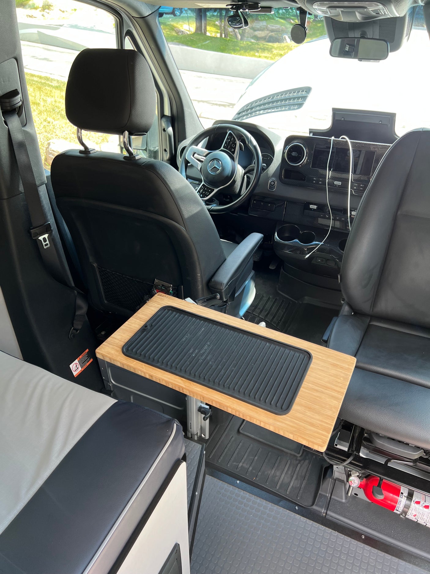 Inside an RV rental, featuring the front cabin with swivel seats, an adjustable table, and a visible fire extinguisher for safety.