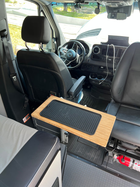 Inside an RV rental, featuring the front cabin with swivel seats, an adjustable table, and a visible fire extinguisher for safety.