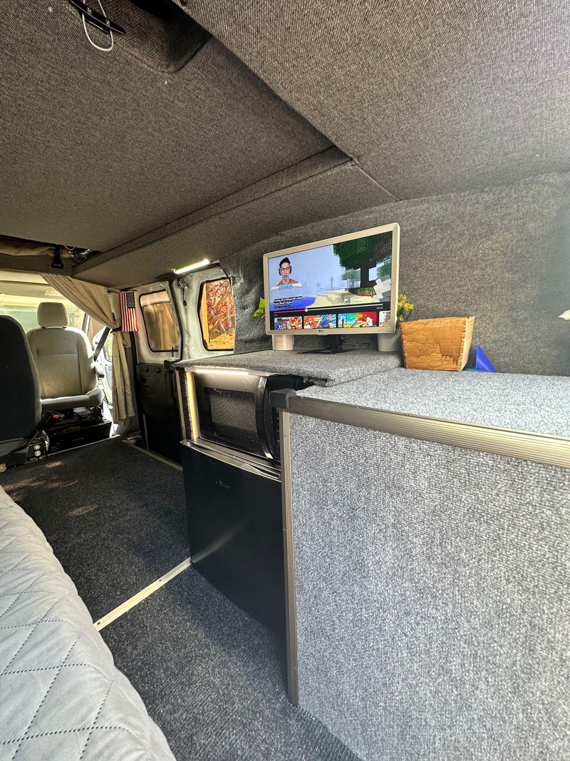  ready for adventure.|White camper van (RV rental) with mountain decals parked on a gravel road beside a rocky hillside.|Inside this rv rental — photo 7