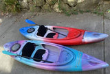 Two vibrant kayaks, red/blue/white and purple/blue/pink, with paddles. Perfect for water sports on your next RV rental trip!