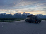 Grand Teton mountains & landscape at sunset/sunrise with an RV rental camper van, bikes on back.