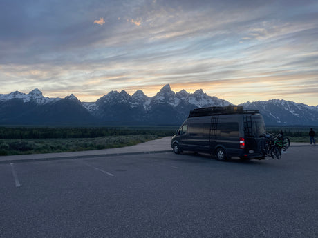 Grand Teton mountains & landscape at sunset/sunrise with an RV rental camper van, bikes on back.