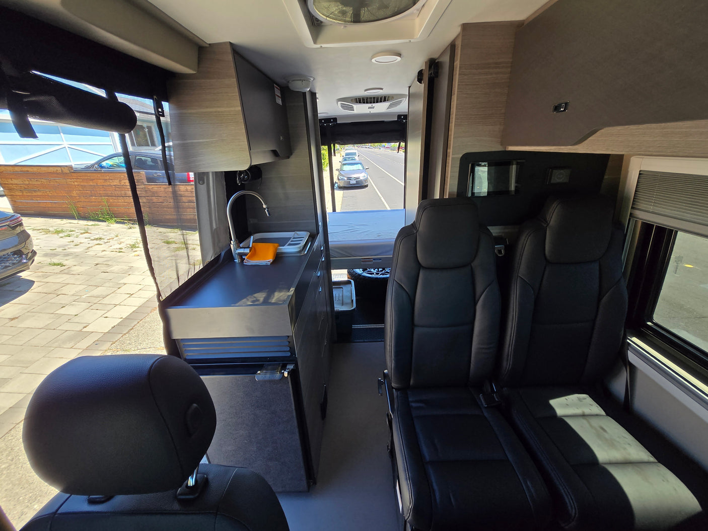 Bright interior of an rv rental, showing the galley kitchen, comfortable seating, and cozy bed in a compact layout.