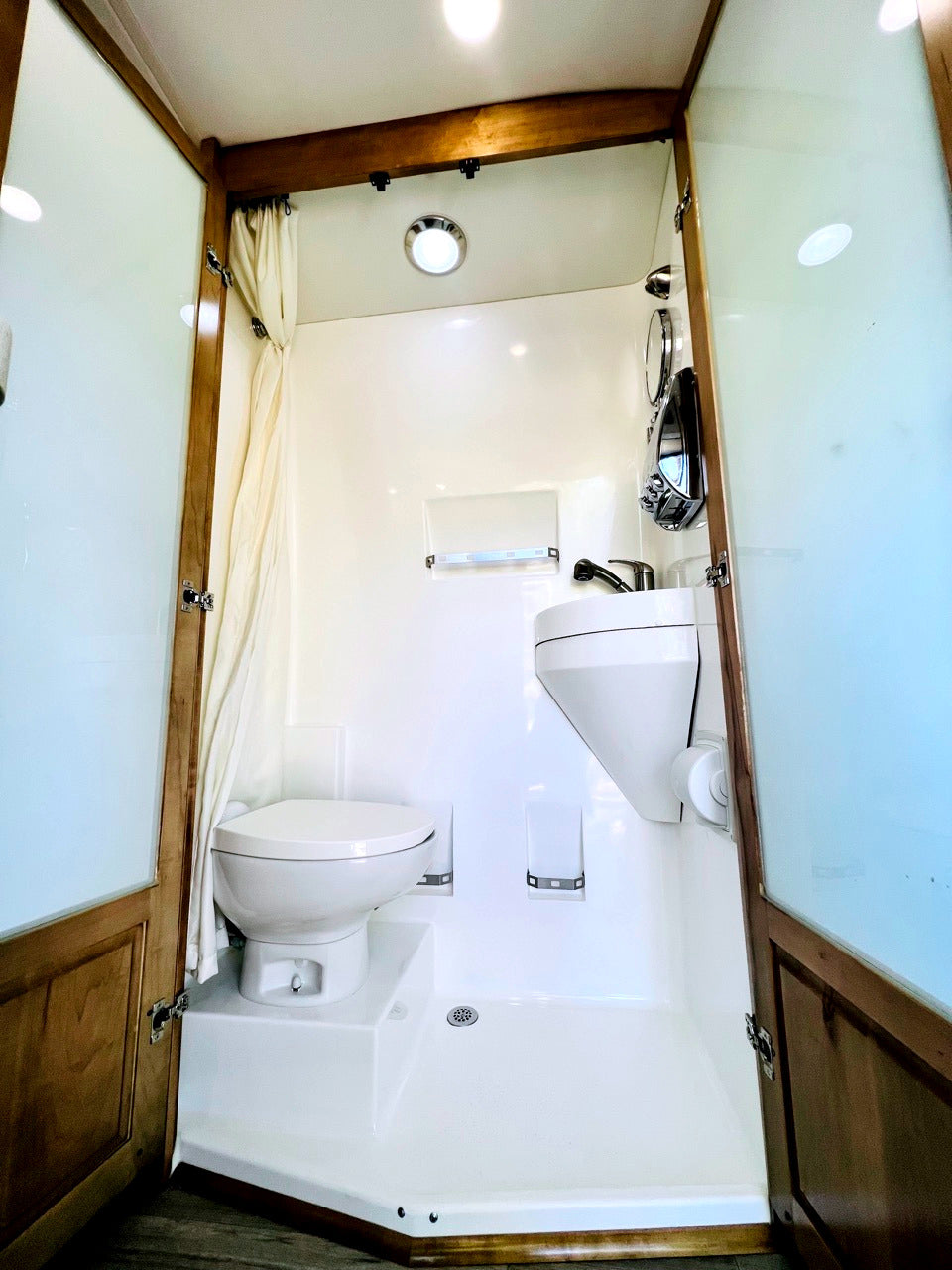 Compact RV rental wet bath with shower, toilet, and sink for comfortable travel convenience.