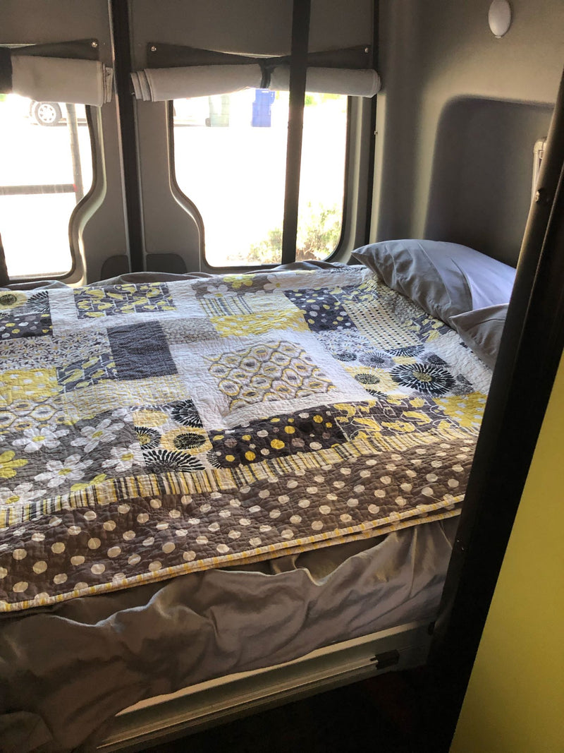  and fire extinguisher for a safe journey.|Inside an RV rental: a bright yellow & gray patterned quilt on a cozy bed — photo 3