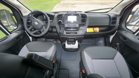 RV rental van interior: dashboard, steering wheel, infotainment, front seats, and center console. Clean & functional.