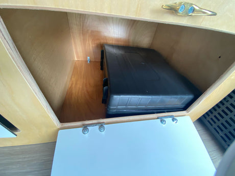 RV rental: Organized storage in an RV kitchen, featuring an open wooden compartment with a portable stove.