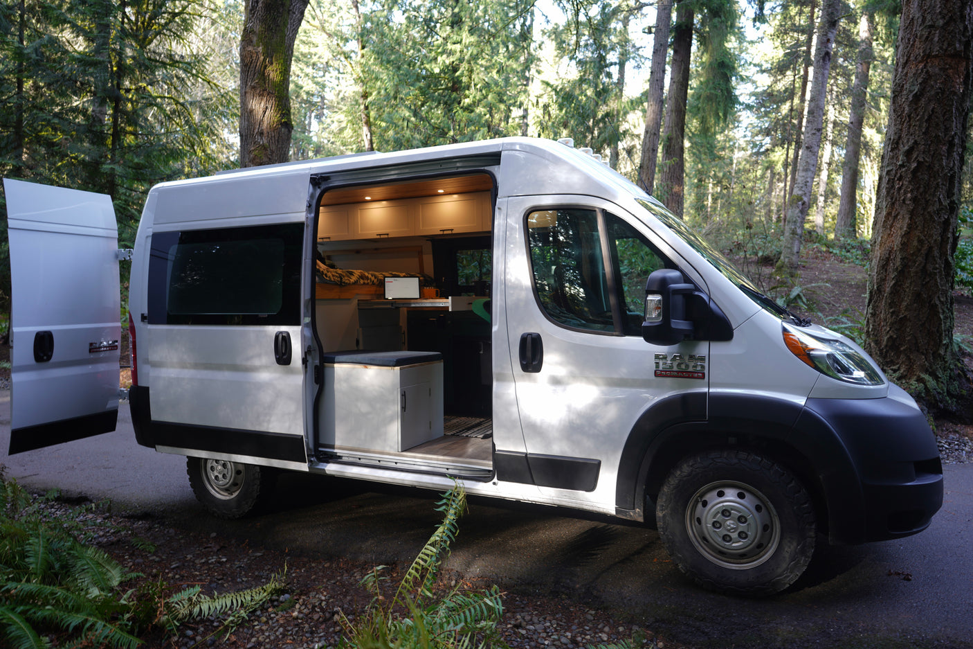 Spacious converted camper van for RV rental, showcasing an inviting interior in a serene forest setting.
