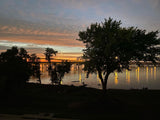 Golden sunset over a lake, bridge lights shimmer. Perfect peaceful stop on your RV rental journey.