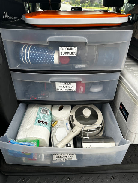 Efficient RV rental organization: clear drawers hold cooking, first aid, electronics, and cleaning supplies for travel.