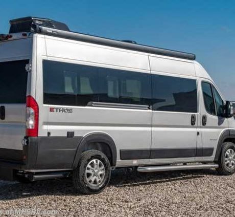 Ethos silver Class B RV rental parked on gravel. Features large tinted windows, a roof awning, and a side step.