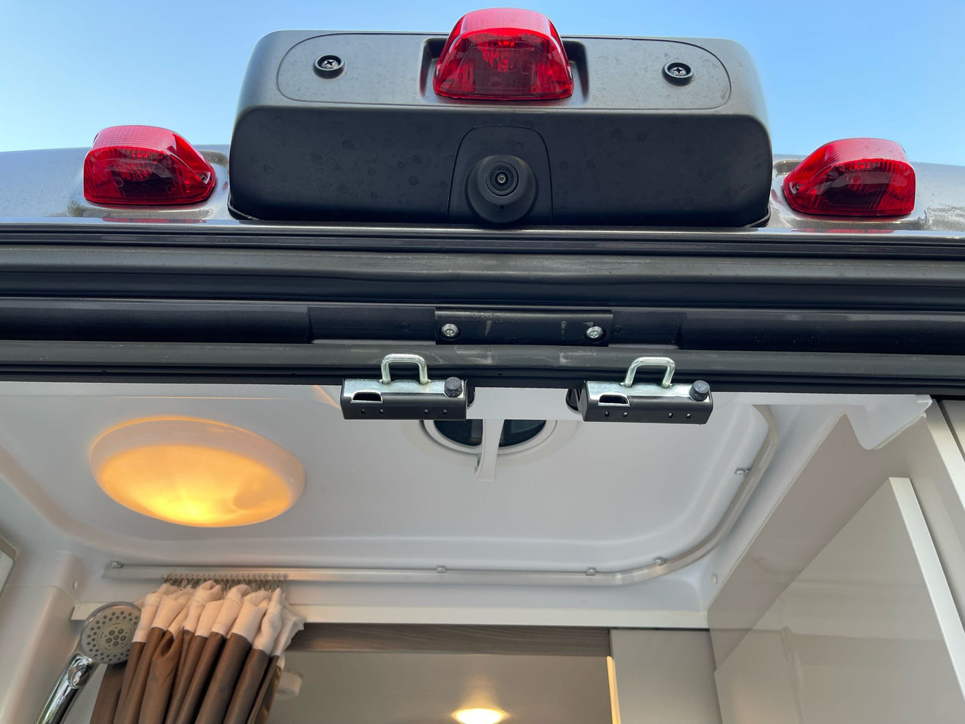 Rear exterior & interior of an RV rental: backup camera, red lights, shower, and ceiling light. Perfect for camper adventures.
