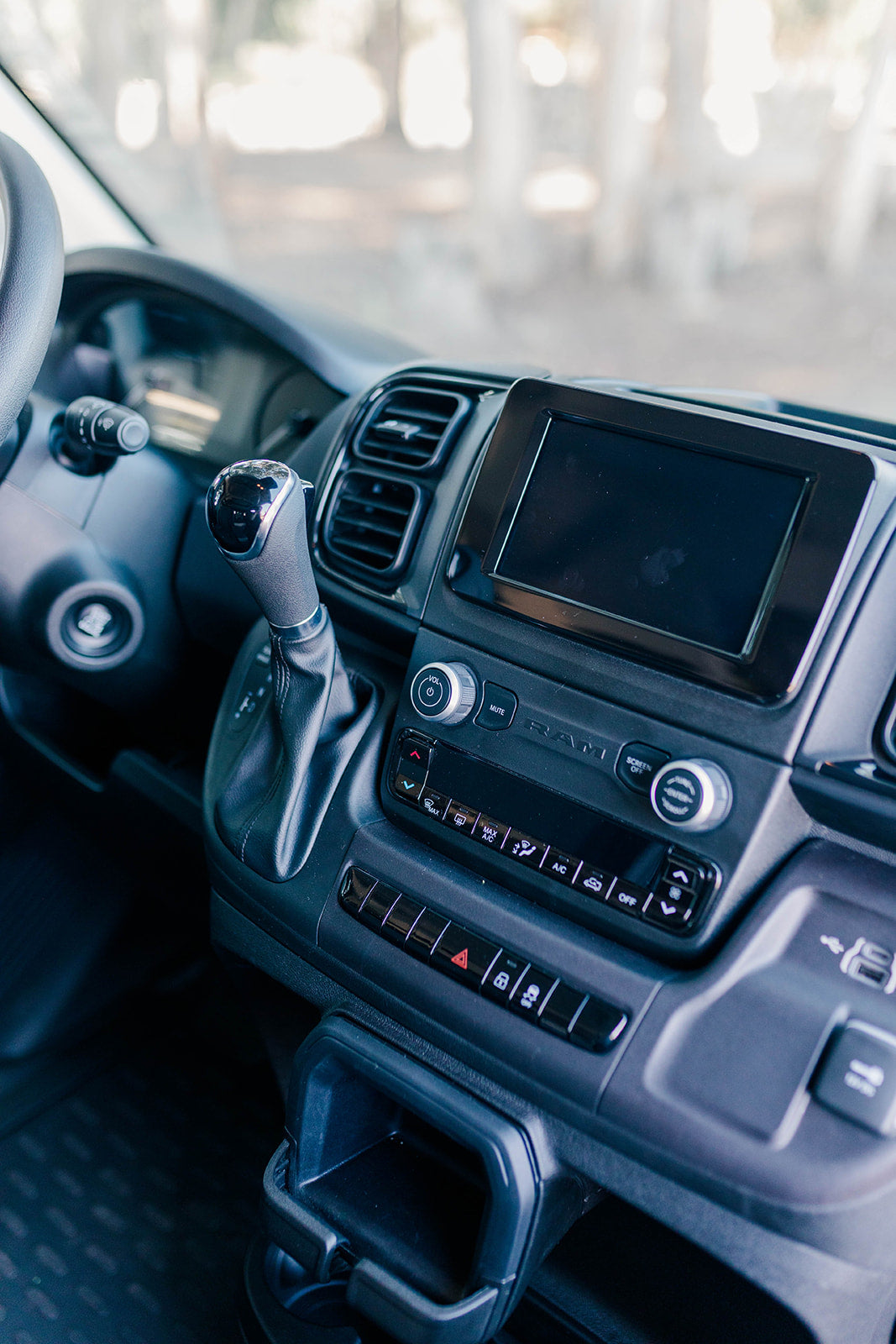 Detail of an RV rental dashboard: automatic gear shifter, infotainment system, and climate control panel.