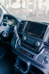 Detail of an RV rental dashboard: automatic gear shifter, infotainment system, and climate control panel.