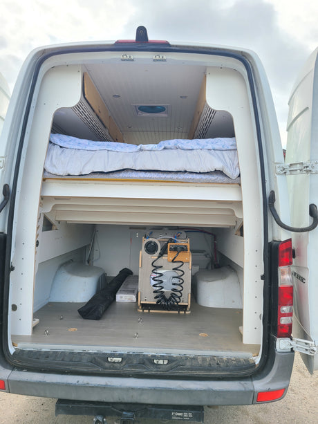 RV rental van interior: custom bed, under-bed storage, and a practical portable water system in the open rear hatch.