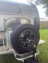 Rear of a compact RV rental, showing a robust off-road spare tire, hitch, and aluminum utility box. Perfect for adventure.