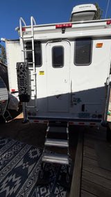 White rv rental camper's rear exterior shows a ladder, entry steps, a Yakima cargo box, and a Nevada license plate.