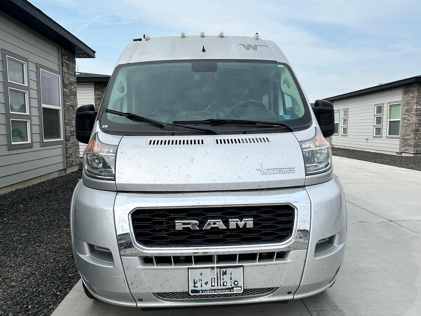  parked outdoors on a clear day.|Silver Winnebago rv rental van (RAM chassis) parked in a driveway. View of the front — photo 3