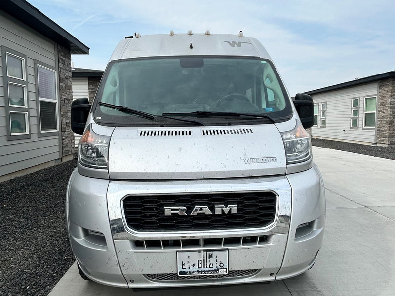 parked outdoors on a clear day.|Silver Winnebago rv rental van (RAM chassis) parked in a driveway. View of the front — photo 3