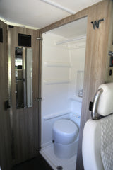 This RV rental's compact wet bath features a white toilet and shower area, designed for efficient camper interior use.
