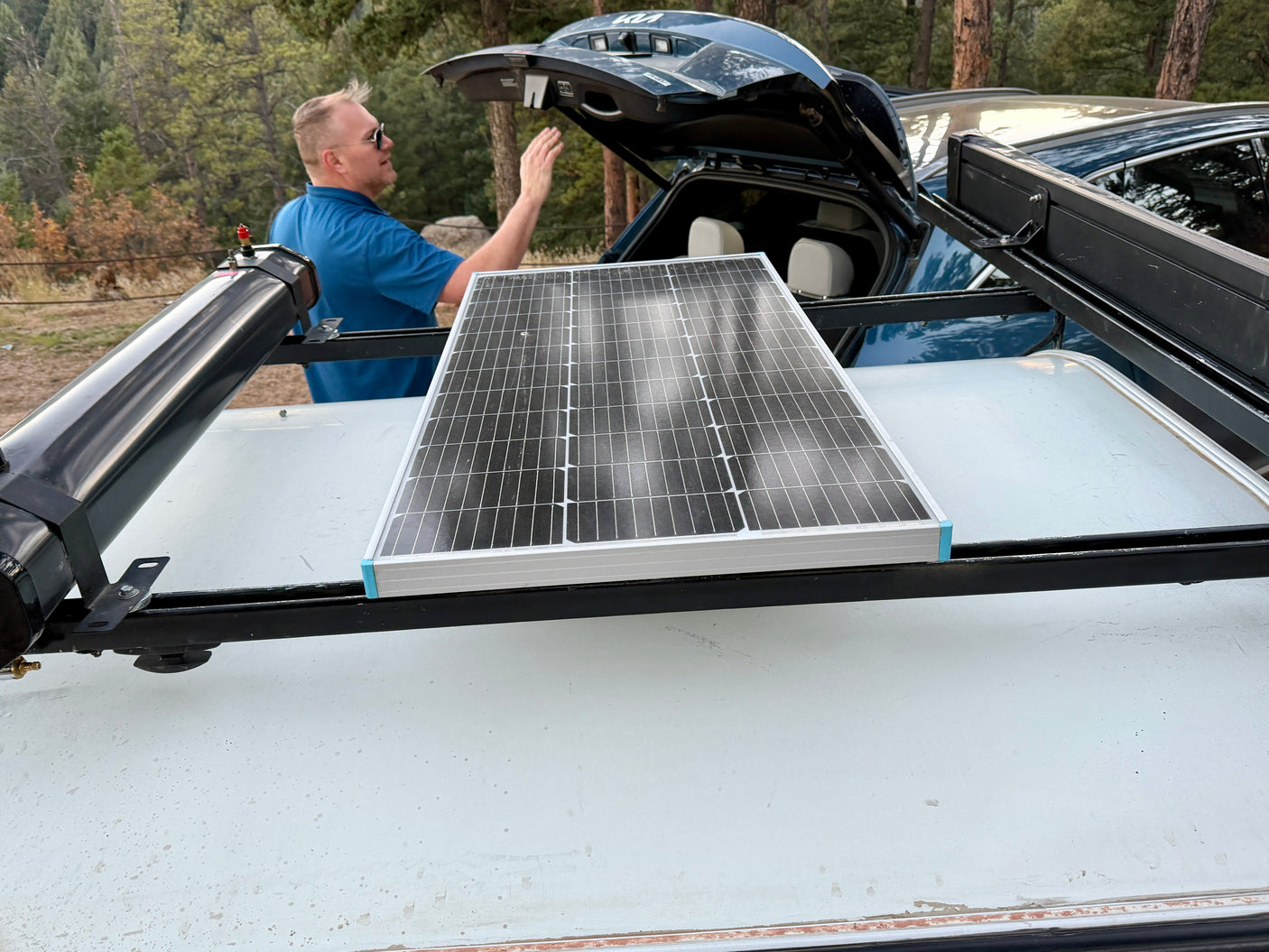 Man preparing a solar panel setup on an RV rental for off-grid camping adventures.