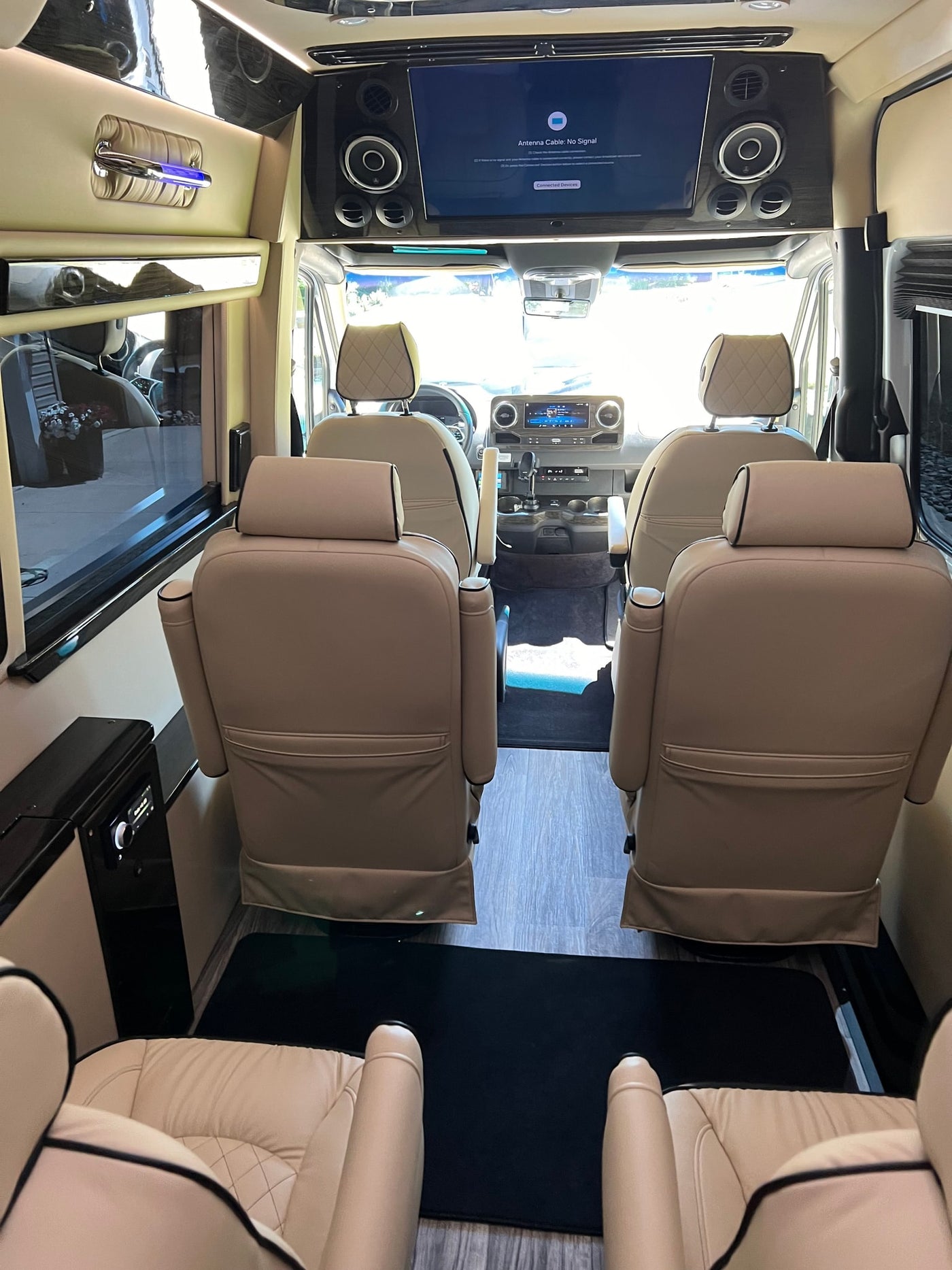 Luxury RV rental interior: tan leather captain's chairs, large screen, plush comfort for travel. — photo 10