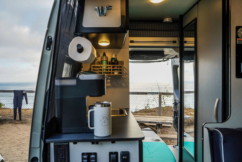  and outdoor cooking area at a lively campsite.|Cozy RV rental night: Relaxing by a warm campfire under a starry sky next to a camper van.|An RV rental interior layout: Features a power lift bed — photo 13