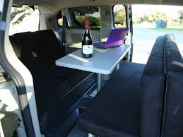 RV rental: Cozy campervan interior with bed, dining/work table (laptop & wine), and bench seating.
