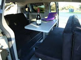 RV rental: Cozy campervan interior with bed, dining/work table (laptop & wine), and bench seating.