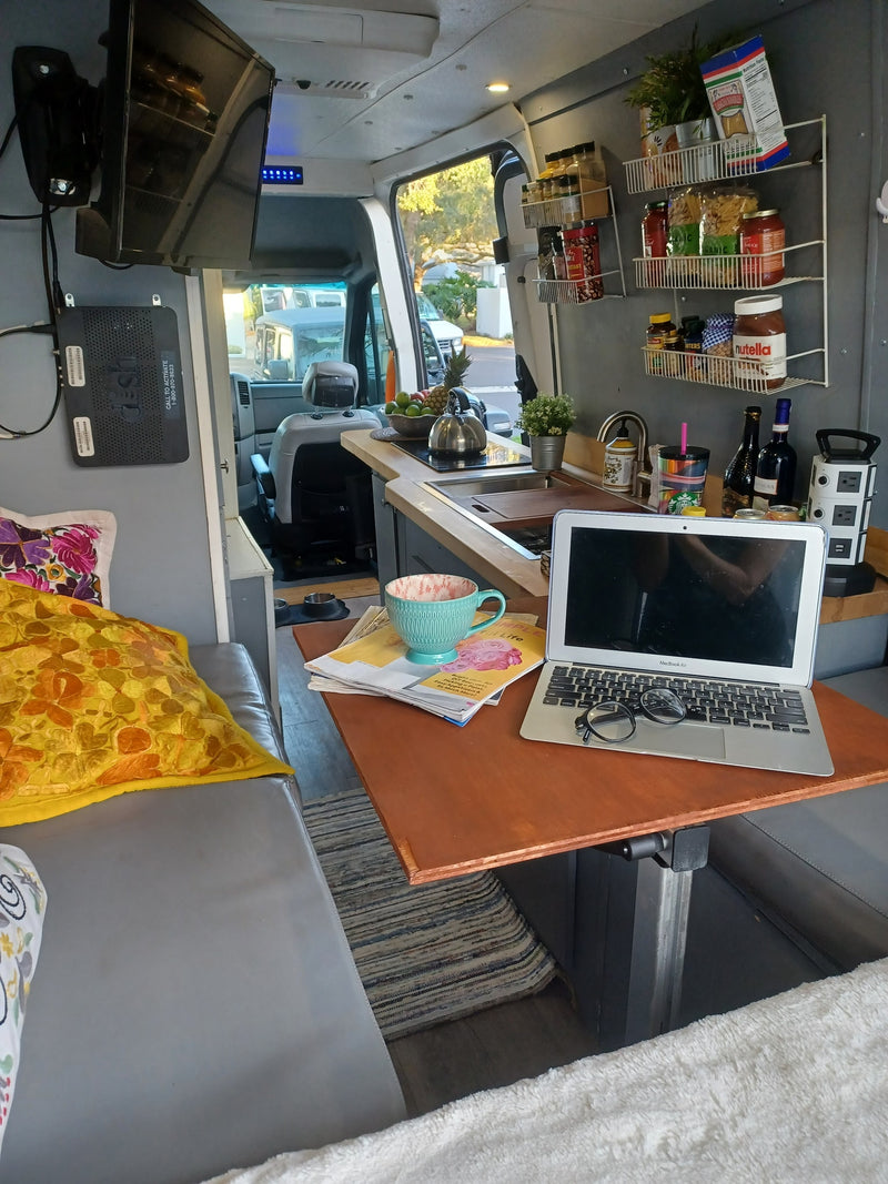 Cozy rv rental interior: kitchen shelves, laptop, TV, and comfy seating make for a practical mobile living space. — photo 5