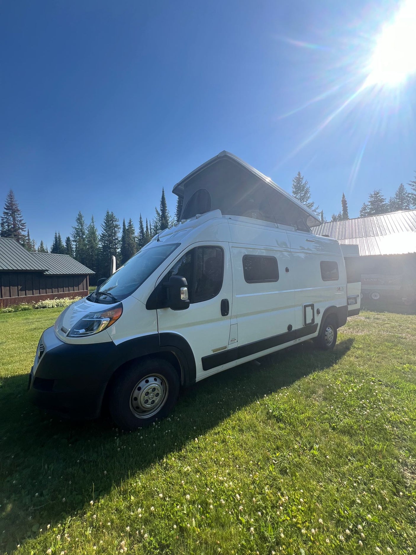White pop-top camper van bathed in sun on a grassy field, ready for your next RV rental adventure.