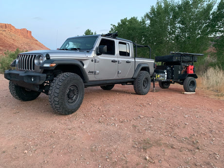 Silver Jeep Gladiator & overland trailer. Ready for off-grid trips, a rugged RV rental alternative.