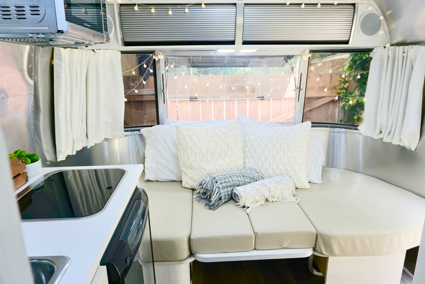 Inside an RV rental: a bright, comfortable living space with a kitchen, curved seating/bed, and charming string lights. — photo 13