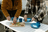 Preparing fresh veggies on a portable table with blue dishes, a perfect setup for healthy eating on your RV rental journey.