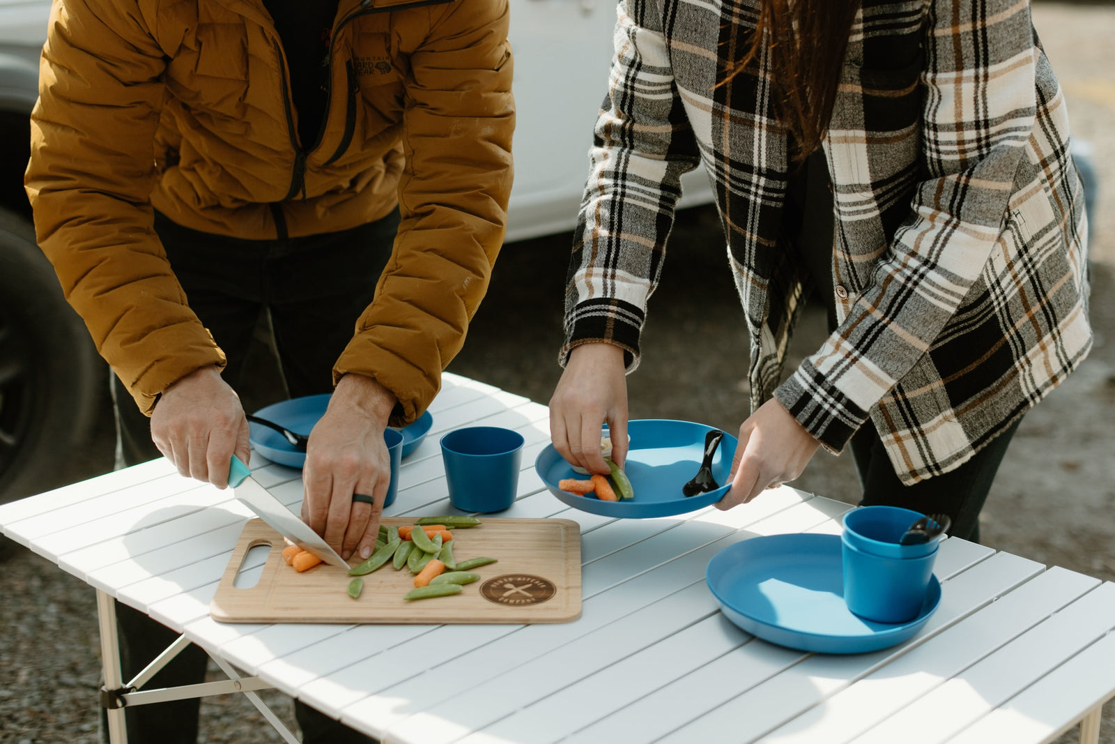 Preparing fresh veggies on a portable table with blue dishes, a perfect setup for healthy eating on your RV rental journey.