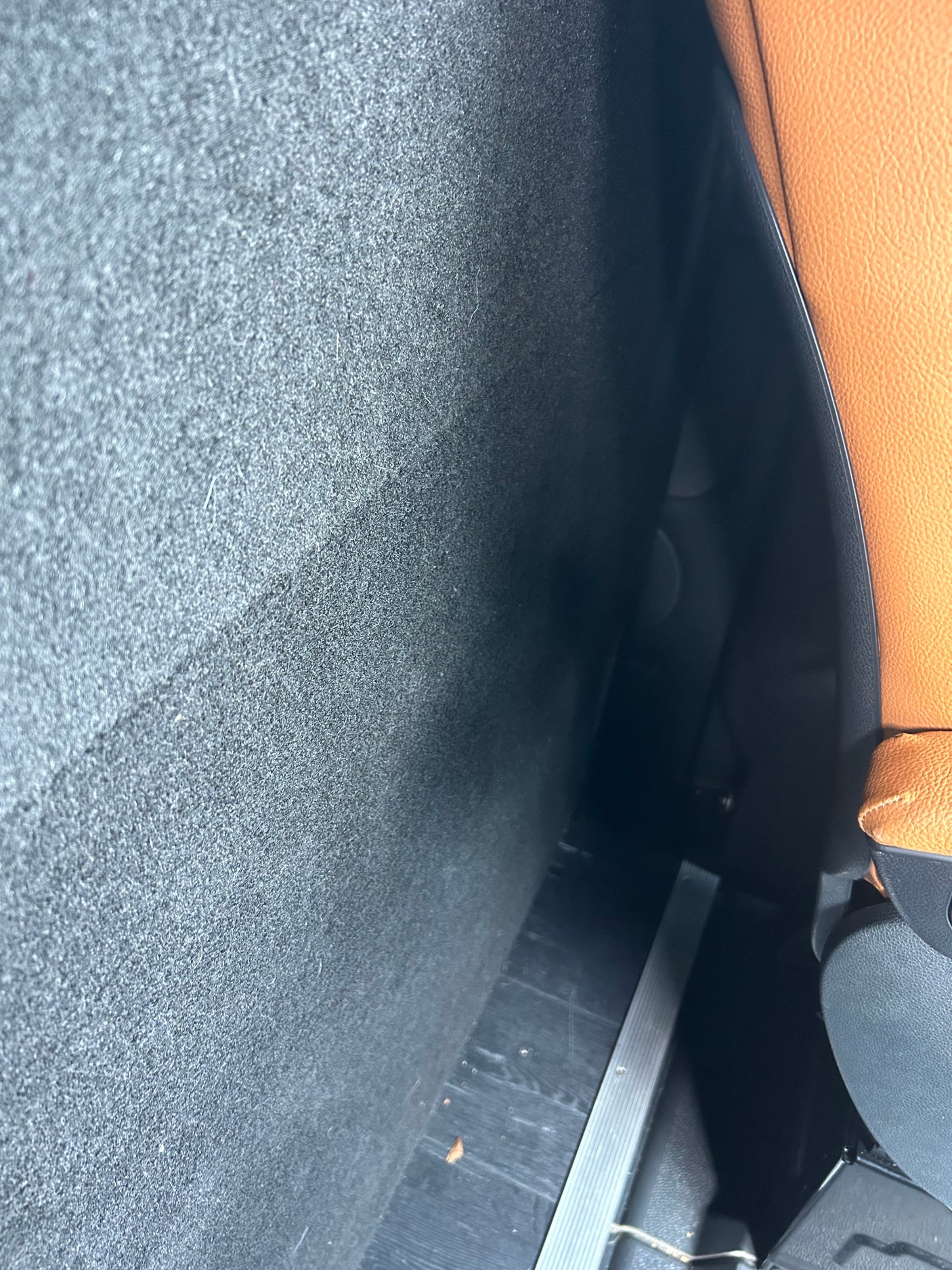 Inside an RV rental: dark gray textured wall, a tan leather seat, and dark floor with metallic trim.
