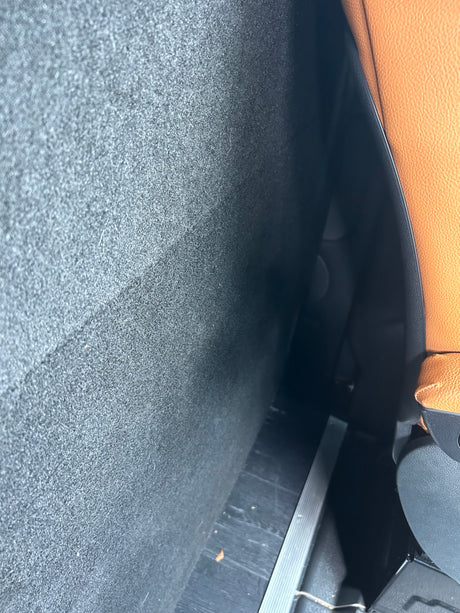 Inside an RV rental: dark gray textured wall, a tan leather seat, and dark floor with metallic trim.